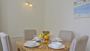 A dining table with chairs, a fruit bowl, and a painting on the wall. - 2 Bed in Southwold (oc-che) (Southwold)