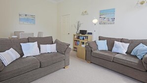 A living room with two grey sofas, a bookshelf, and two paintings on the walls. - 2 Bed in Southwold (oc-che) (Southwold)