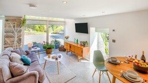 Ein modernes Wohnzimmer mit einer Couch, einem Couchtisch und einem Essbereich mit Tisch für zwei Personen.
