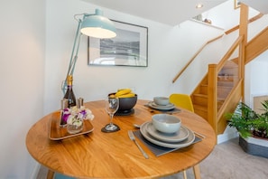 A dining area with a round wooden table, a modern lamp, a bowl of fruit, and a framed picture on the wall. - 1 Bed in Dolgellau (oc-bow292) (Brithdir and Llanfachreth)