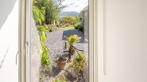 Blick durch ein Fenster auf einen Kiesweg, Kübelpflanzen und einen Garten.