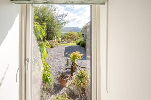 A view through a window with a gravel path, potted plants, and a garden. - 1 Bed in Dolgellau (oc-bow292) (Brithdir and Llanfachreth)