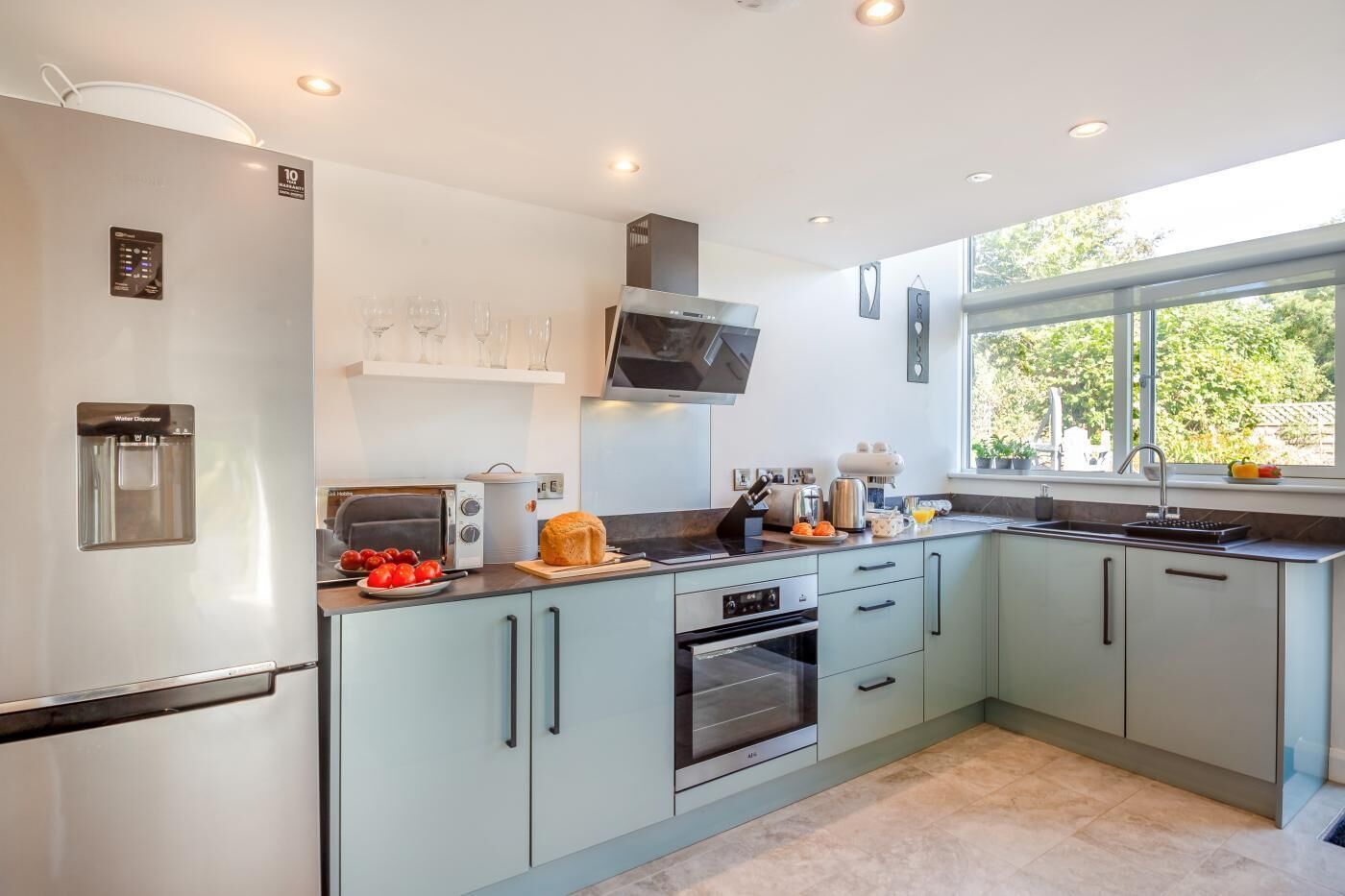 A modern kitchen with a built-in water dispenser, a microwave, an oven, and a window providing natural light.