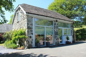 A stone building with large windows, a gravel driveway, and potted plants. - 1 Bed in Dolgellau (oc-bow292) (Brithdir and Llanfachreth)