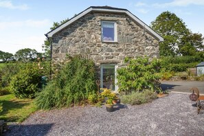 A stone house with a sloped roof, a visible window, and a gravel driveway. - 1 Bed in Dolgellau (oc-bow292) (Brithdir and Llanfachreth)