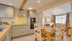 Une cuisine moderne avec un coin repas. Elle comprend une cuisinière, un four et une table à manger avec quatre chaises.