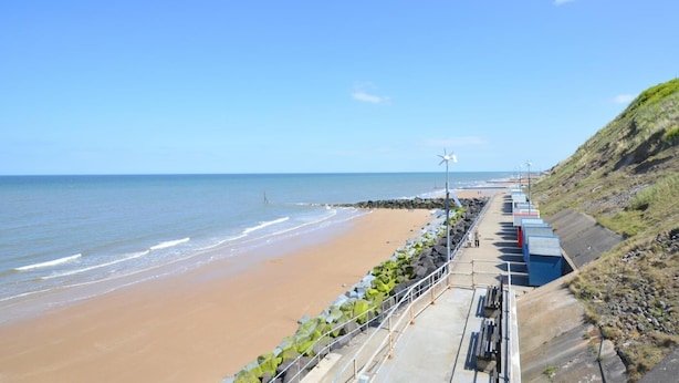 Une promenade en bord de mer offrant une vue sur la plage et l’océan.
