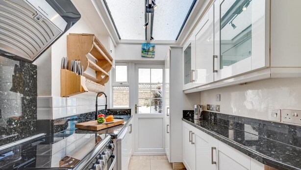 Une cuisine moderne dotée d’une verrière, d’appareils électroménagers en acier inoxydable et offrant une vue sur l’extérieur.