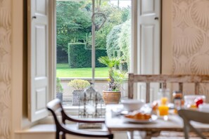 A dining area with a view of a well-maintained garden through open doors. - 8 Bed in Gilling West (oc-g33289) (Gilling West)
