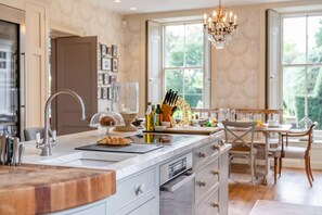 A modern kitchen with a marble countertop, a built-in oven, and a dining area with a wooden table and chairs. - 8 Bed in Gilling West (oc-g33289) (Gilling West)
