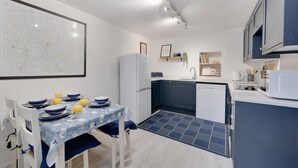 Una cocina compacta con una mesa de comedor, un refrigerador blanco y un microondas.