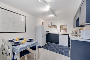 A compact kitchen with a dining table, white refrigerator, and a microwave. - 1 Bed in Jedburgh (oc-nb1951) (Jedburgh)