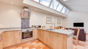 A modern kitchen with a large island, built-in oven, and a skylight. - 2 Bed in Southwold (oc-weh) (Southwold)