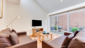 A modern living room with a sofa set, a TV, and a small table with cups and a tray. - 2 Bed in Southwold (oc-weh) (Southwold)
