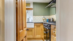 A kitchen with wooden cabinets, a stove, and a sink. - 2 Bed in Bolton By Bowland (oc-p33306) (Bolton by Bowland)