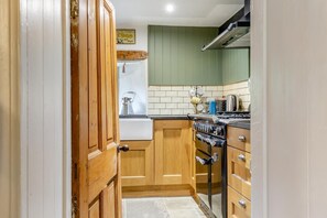 A kitchen with wooden cabinets, a stove, and a sink. - 2 Bed in Bolton By Bowland (oc-p33306) (Bolton by Bowland)