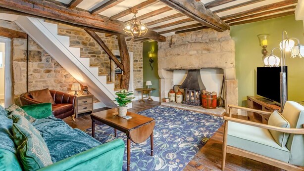 A rustic interior with a stone fireplace, wooden beams, a staircase, and a cozy seating area. - 2 Bed in Bolton By Bowland (oc-p33306) (Bolton by Bowland)