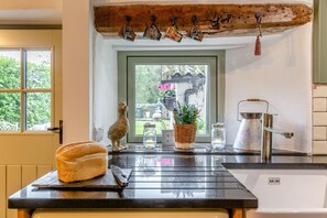 A kitchen with a loaf of bread on the counter, a coffee maker, and a hanging coffee mug rack. - 2 Bed in Bolton By Bowland (oc-p33306) (Bolton by Bowland)