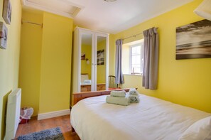 A bedroom with a bed, a wardrobe, a window with curtains, and a radiator. - 2 Bed in Holt (oc-1267) (Holt)