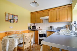 A compact kitchen with wooden cabinets, a microwave, a stove, and a sink. - 2 Bed in Holt (oc-1267) (Holt)
