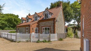 A two-story house with a stone facade and a white picket fence. - 2 Bed in Blakeney (oc-1558) (Blakeney)