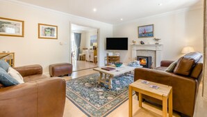 A living room with a fireplace, a television, and a dining area. - 2 Bed in Blakeney (oc-1558) (Blakeney)