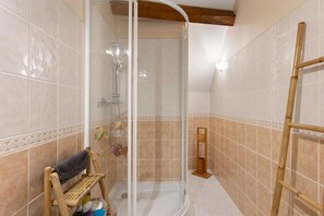 Eine Dusche mit Glastür, eine Holzbank und eine Leiter.