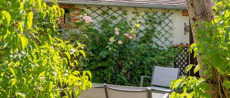 A garden with a bench, a lattice wall, and a building with a tiled roof.