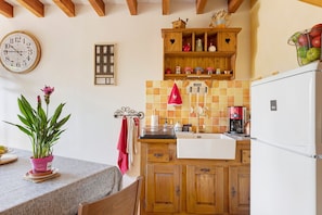 A kitchen with wooden cabinets, a sink, a clock, and a potted plant. - Guest Room 'Chambre Hiver' with Shared Garden and Wi-Fi (Villefranche-sur-Cher)