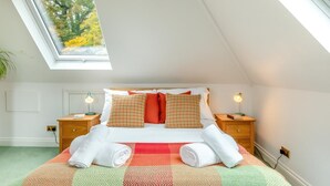 A bedroom with a skylight, a bed with patterned pillows, two bedside tables with lamps, and a view of trees outside. - 1 Bed in Clatcombe (oc-s33309) (Castleton)