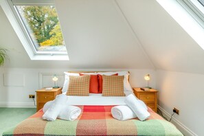 A bedroom with a skylight, a bed with patterned pillows, two bedside tables with lamps, and a view of trees outside. - 1 Bed in Clatcombe (oc-s33309) (Castleton)