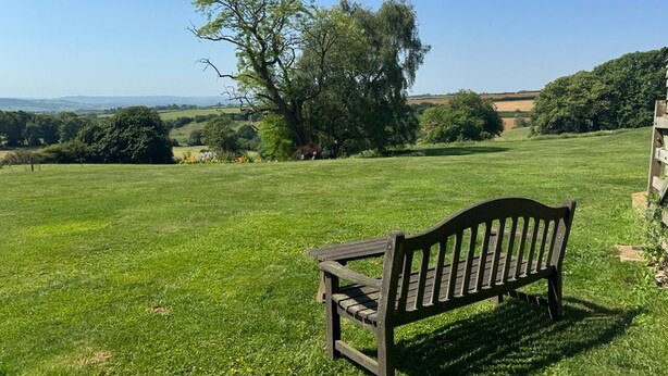 A bench in a grassy field with trees and a clear sky. - 1 Bed in Clatcombe (oc-s33309) (Castleton)