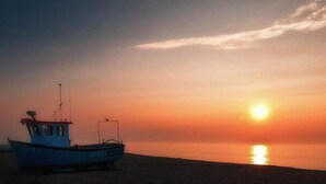Een boot op het strand bij zonsondergang.