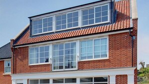 Een tweelaags bakstenen huis met een plat dak, grote ramen en een zichtbare garage.