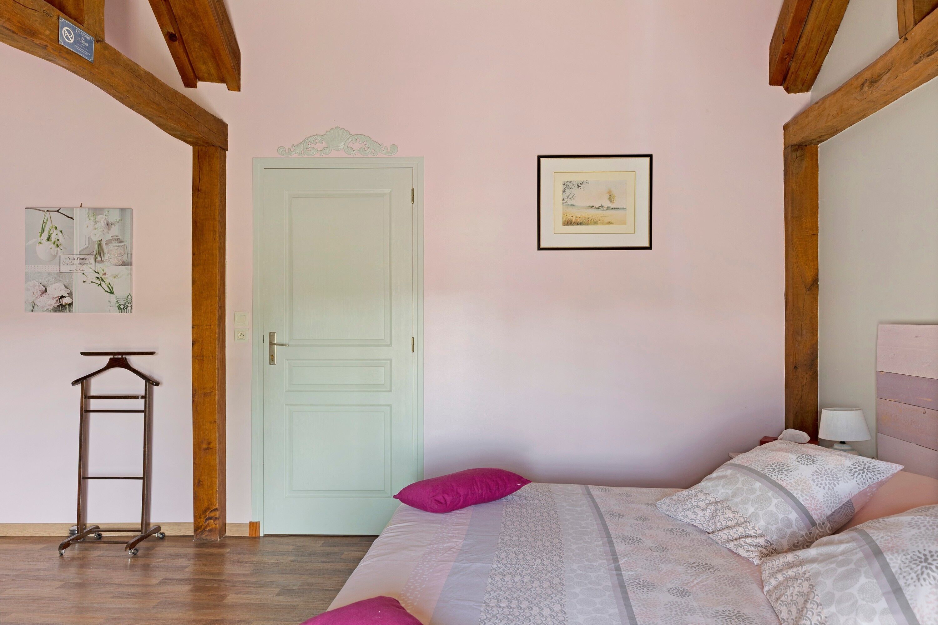 Une chambre à coucher avec un lit, une porte, un tableau encadré et une petite table.