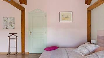Une chambre à coucher avec un lit, une porte, un tableau encadré et une petite table.