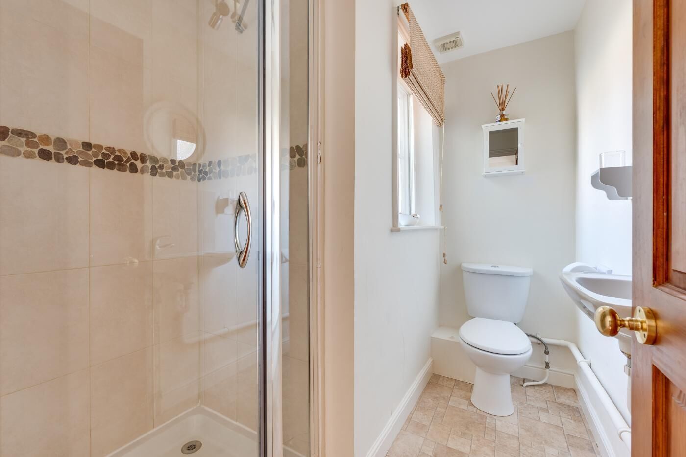 A bathroom with a glass-enclosed shower, a toilet, and a sink.