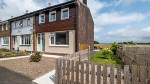 Ein zweistöckiges Wohnhaus mit Backsteinfassade, zahlreichen Fenstern und einem kleinen Garten mit Holzzaun.