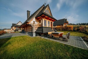 Eine Blockhütte mit geneigtem Dach, einem Schornstein und einer Terrasse mit Bänken.