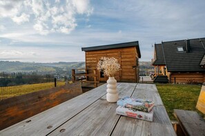 Eine Holzterrasse mit einem Tisch, einer Vase mit getrockneten Blumen und einem Buch mit dem Titel 'Kryminalne Zakopane'.