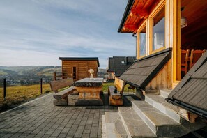 Eine Holzhütte mit einer terrasse aus Steinplatten, einem Holztisch und Bänken.