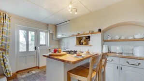 A kitchen with a central island, white cabinetry, and a breakfast bar. - 1 Bed in Woodbridge (oc-hok) (Bawdsey)