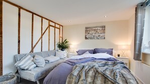 A bedroom with a bed, a sofa, a potted plant, and a wall-mounted artwork. - 2 Bed in Peasmarsh (oc-rh1172) (Peasmarsh)