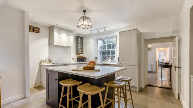 Una cocina moderna con una isla grande, taburetes de bar y una ventana que proporciona luz natural.
