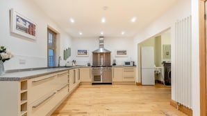 Een moderne keuken met houten vloeren, roestvrijstalen apparatuur en lichtkleurige kastjes.