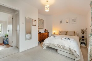Een slaapkamer met een bed, een kaptafel, een spiegel en kunstwerken aan de wanden.