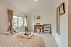 A bedroom with a bed, a desk, and a chair. There is a window with curtains, a radiator, and a framed picture on the wall. - 3 Bed in Milford On Sea (oc-f33344) (Milford on Sea)