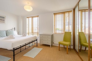 Una camera da letto con un letto, un termosifone, uno specchio e due sedie.