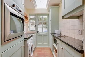 A compact kitchen with a washing machine, a built-in oven, and a skylight above the door.
