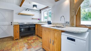 A modern kitchen with wooden cabinets, a stainless steel stove, and a built-in dishwasher. - 4 Bed in Eastbridge (oc-bricot) (East Bridge)